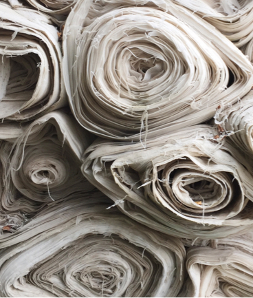 the ends of a bunch of stacked rolls of off-white textiles